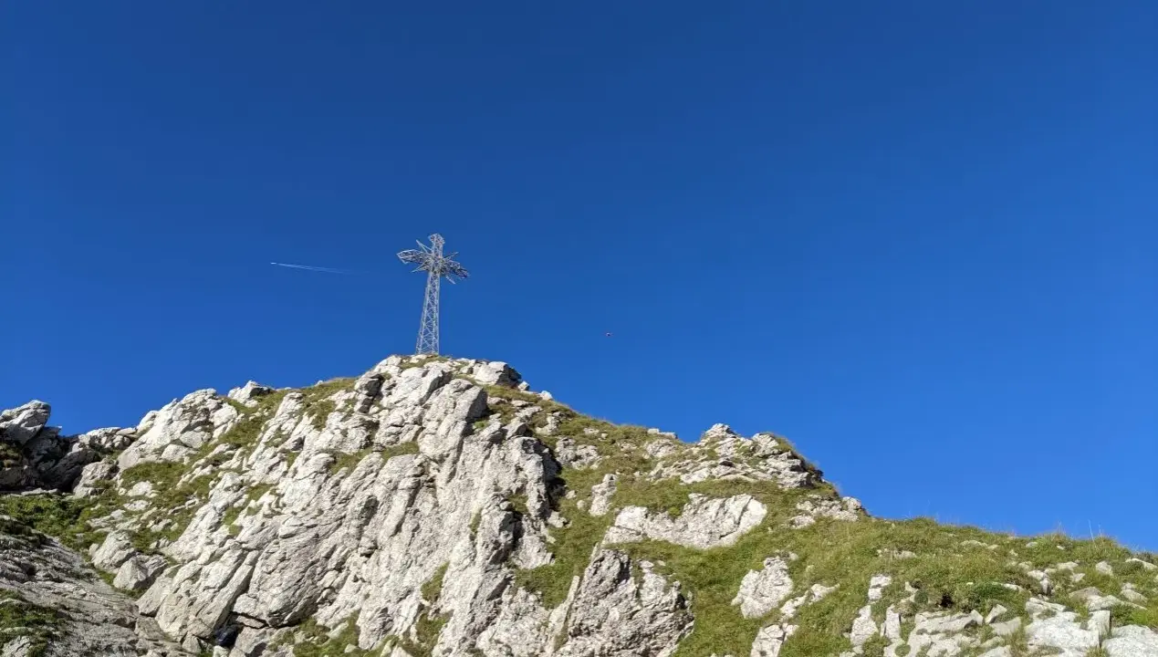Giewont dla początkujących: krzyż na szczycie, skaliste zbocza porośnięte trawą i błękitne niebo. Idealny cel wędrówki.