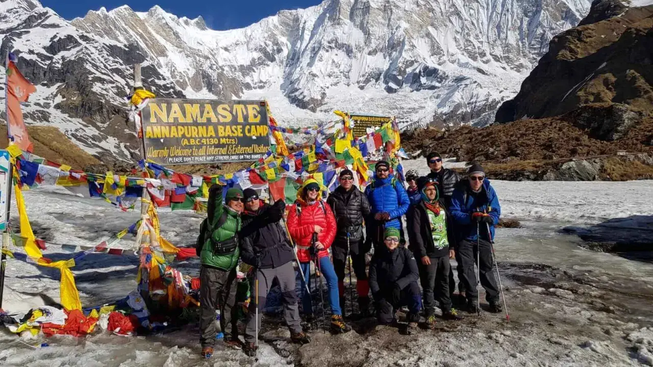 Grupa turystów na tle Annapurny podczas trekking w Nepalu. W tle majestatyczne, ośnieżone szczyty i kolorowe flagi modlitewne.