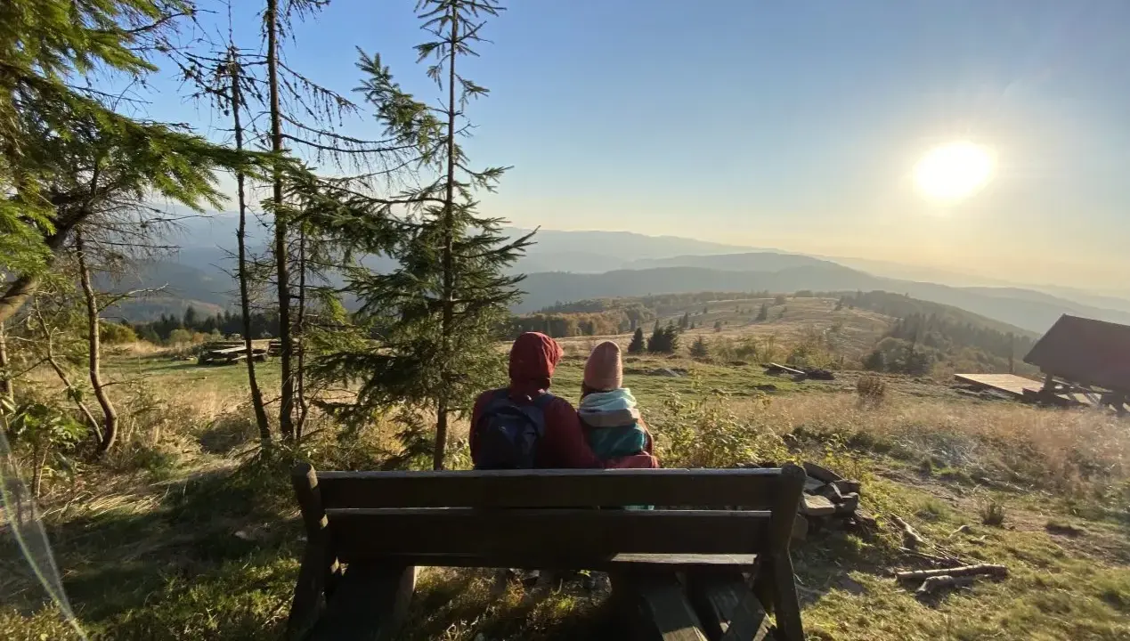 Para siedzi na ławce, podziwiając widok na Beskid Wyspowy. To z pewnością najładniejszy szlak na Mogielicę, z tak pięknym zachodem słońca.