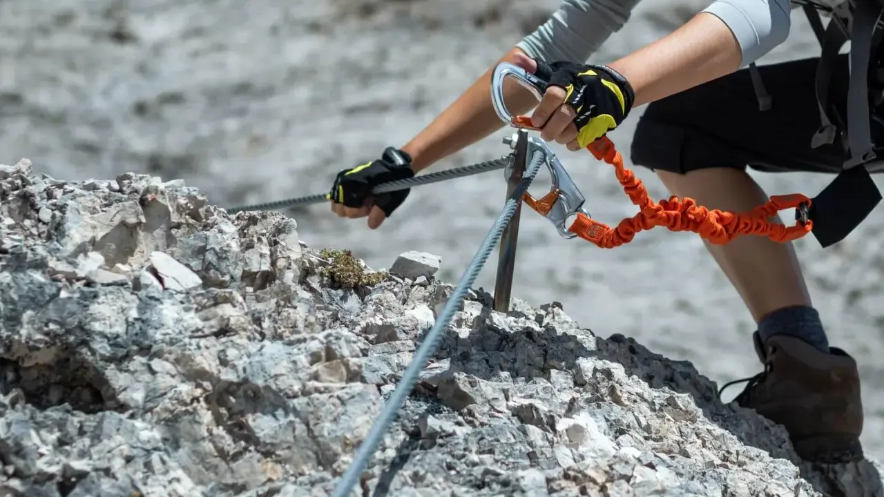 Ręce w rękawiczkach trzymają się stalowej liny na via ferrata. To część ekscytujących szlaków na Słowacji.