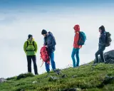 Czterech turystów w górskim krajobrazie, przygotowujących się do wyprawy. To właśnie jest co to trekking – przygoda i odkrywanie.