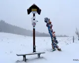 Zimowy dzień, tabliczka z drogowskazami i kolorowa rzeźba. Może to skopiec najkrótszy szlak?