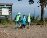 Rodzina na szczycie Baraniej Góry. Dzieci z kijkami trekkingowymi, mama klęczy obok.