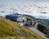 Widok na Kasprowy Wierch szlak z kolejką linową i budynkami, nad morzem chmur.