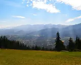 Widok na Zakopane z Gubałówki. Słońce przebija się przez chmury, oświetlając miasto i góry. Zastanawiasz się, ile się idzie na Gubałówkę?