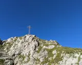 Giewont dla początkujących: krzyż na szczycie, skaliste zbocza porośnięte trawą i błękitne niebo. Idealny cel wędrówki.