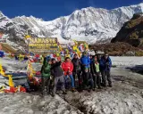 Grupa turystów na tle Annapurny podczas trekking w Nepalu. W tle majestatyczne, ośnieżone szczyty i kolorowe flagi modlitewne.