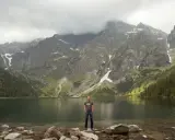 Mężczyzna na kamieniach nad jeziorem, w tle góry i chmury. Piękna morskie oko trasa.
