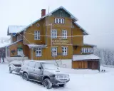 Schronisko na Śnieżniku w zimowej scenerii. Samochód z przyczepą i turyści przy wejściu. Masyw Śnieżnika i jego szlaki w śniegu.