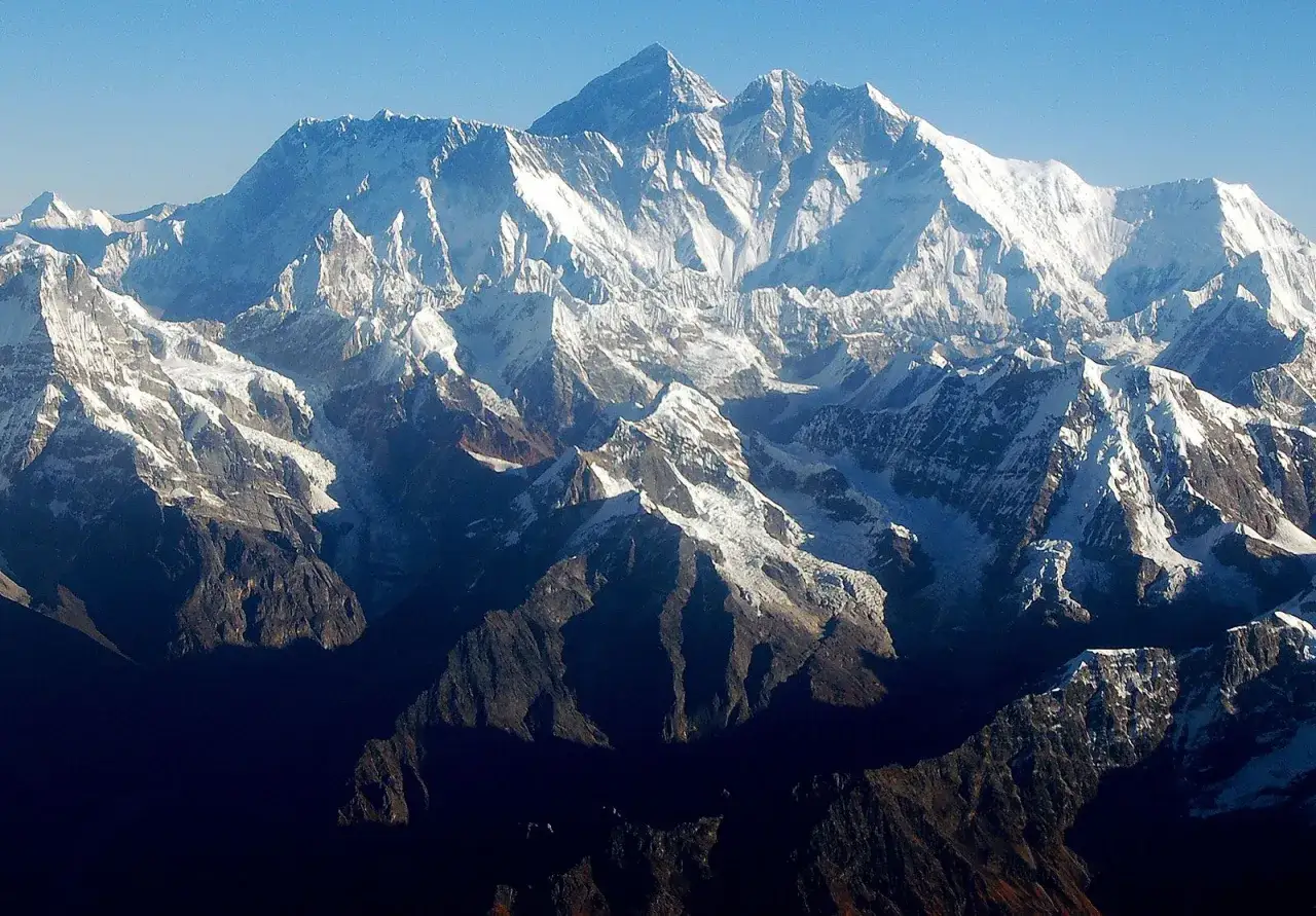Majestatyczny szczyt Mount Everest w Himalajach, pokryty śniegiem i lodem, góruje nad innymi górami.