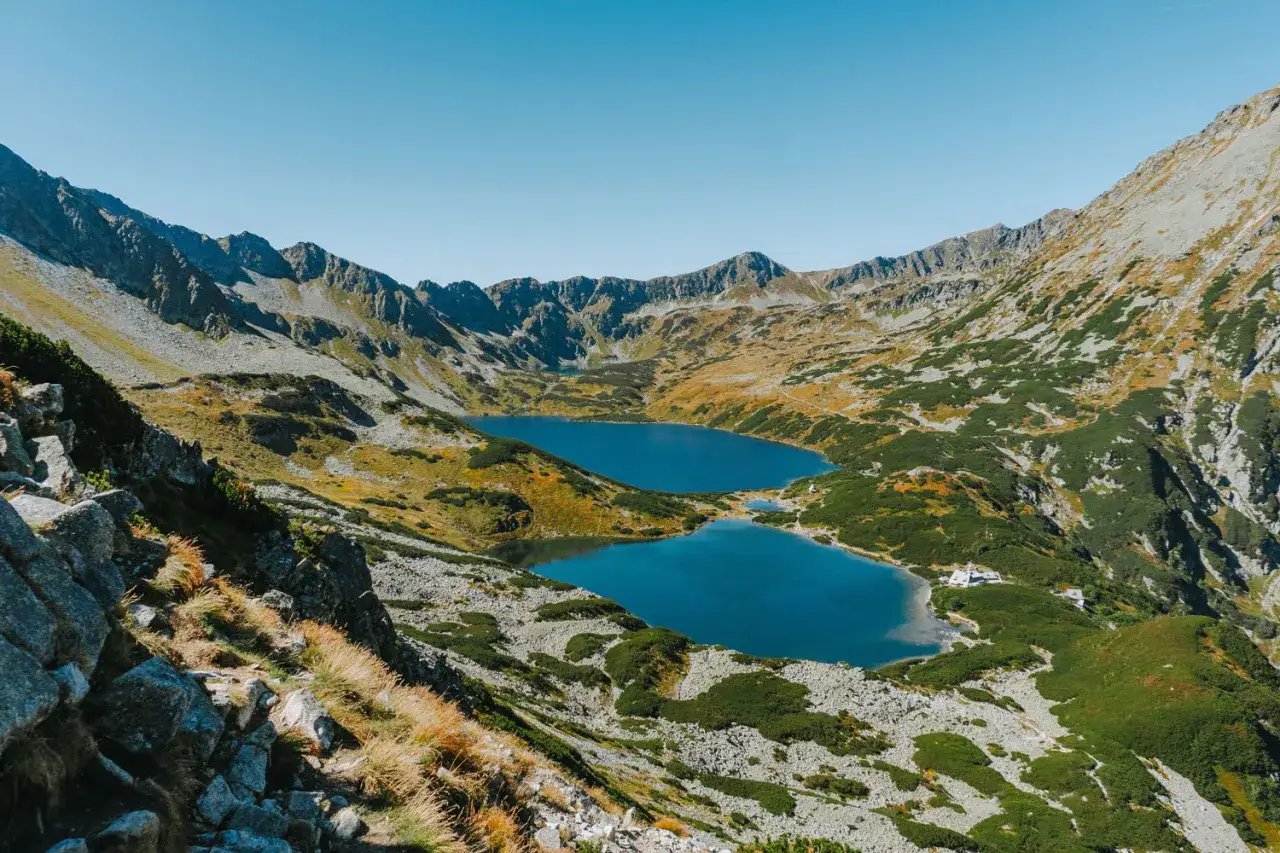 Widok na Morskie Oko i Dolinę Pięciu Stawów w jeden dzień. Błękitne jeziora otoczone skalistymi szczytami i jesienną roślinnością.