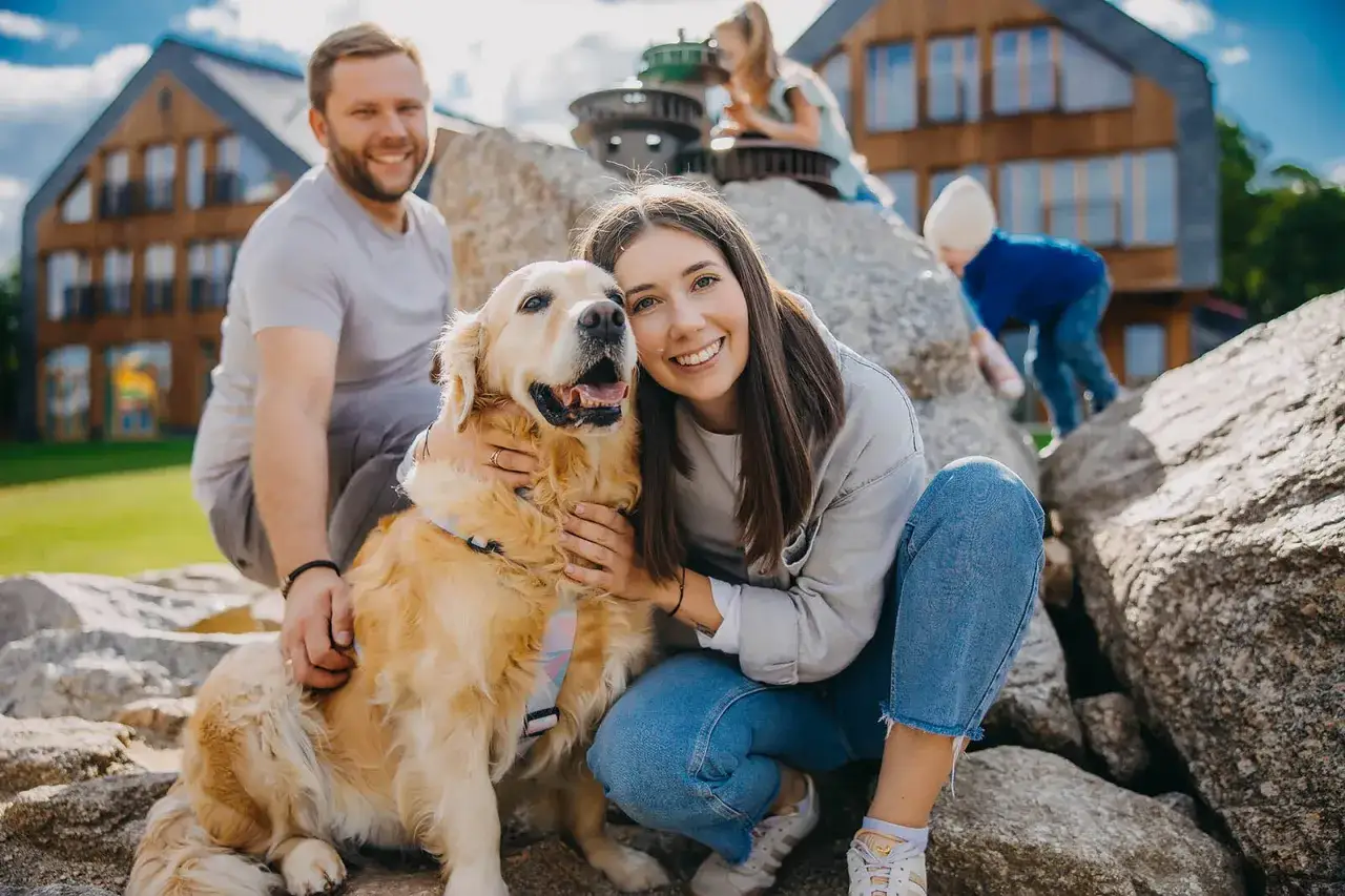 Uśmiechnięta rodzina z psem na kamieniach. Czy na Śnieżkę można z psem? Tak, jeśli jest tak szczęśliwy jak ten złoty retriever!