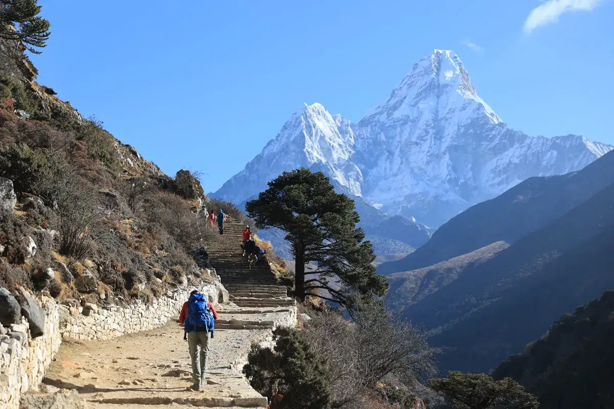 Trekking Everest Base Camp: grupa turystów wspina się po kamiennych schodach w kierunku ośnieżonych szczytów Himalajów.
